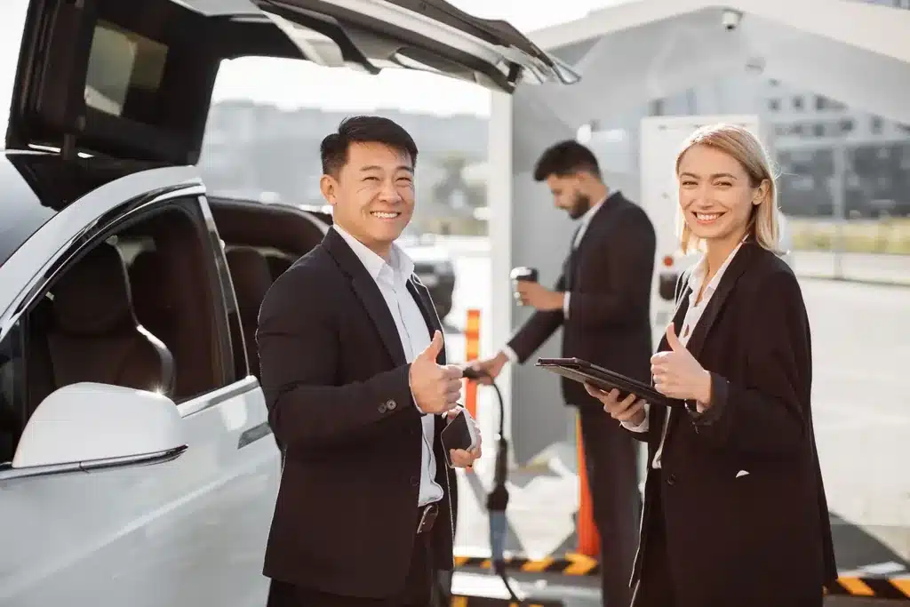 Chauffeur VTC et clients d'affaires, pouce levé, à leur arrivée à l'aéroport