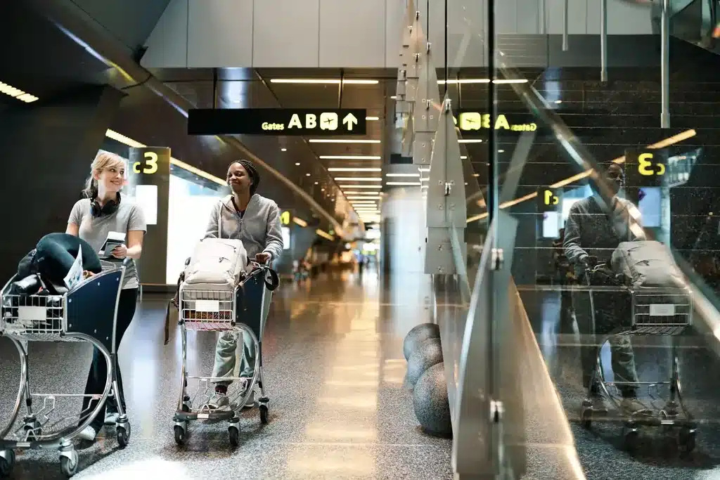 Passagers et chariots à bagages dans le hall des arrivées, avant leur transfert en VTC